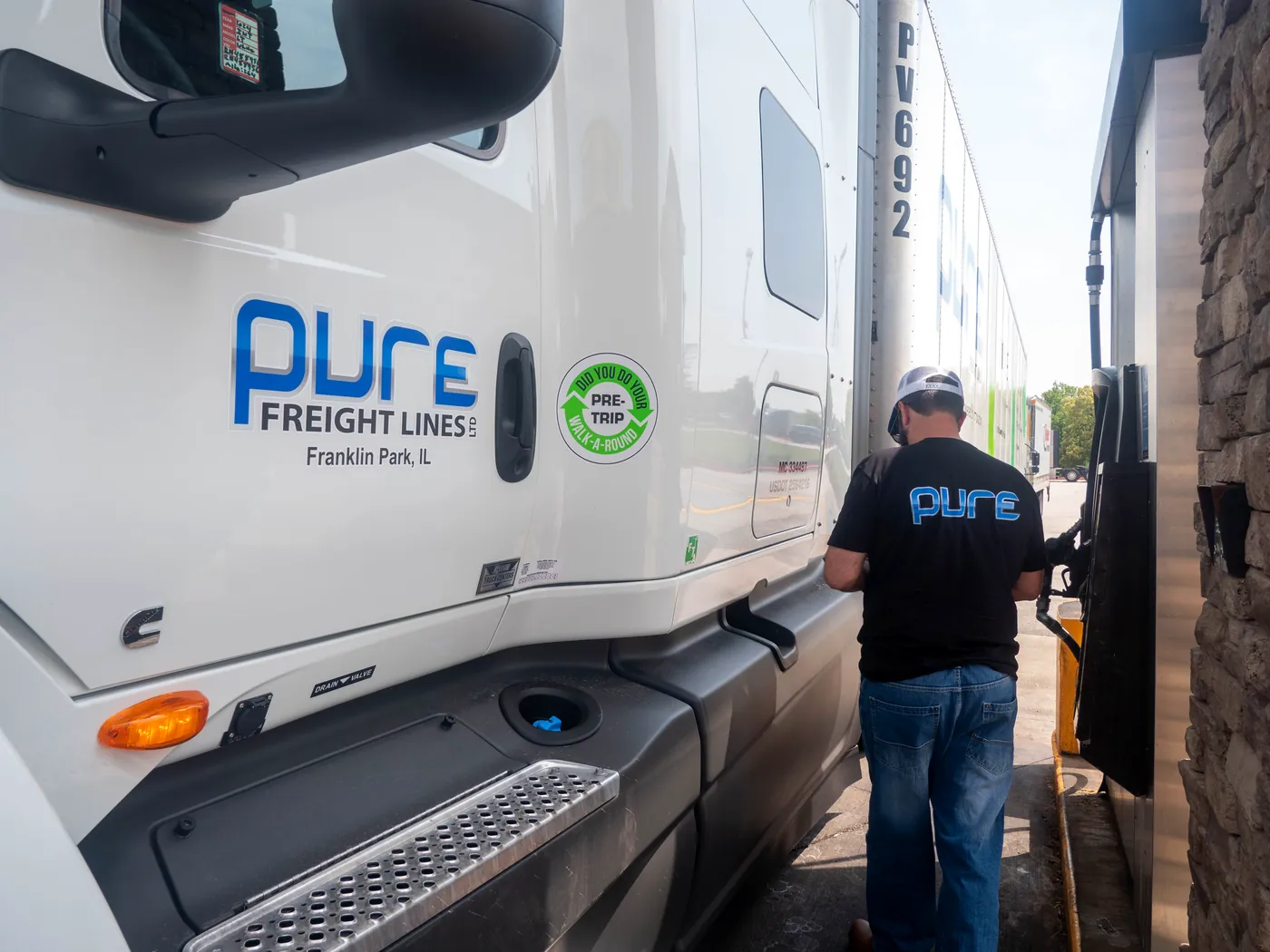Pure Freight Lines cab door with a driver fueling